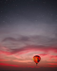 red and black hot air balloon flying on the sky during golden hour thumbnail