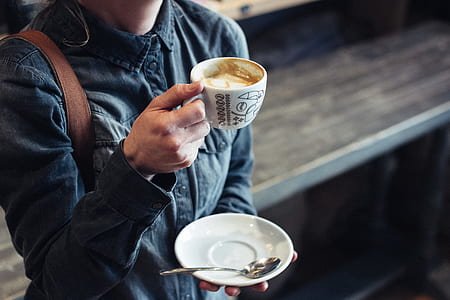 woman holding cup of latte and saucer thumbnail