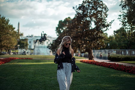 woman walking on grass field near tree during daytime thumbnail