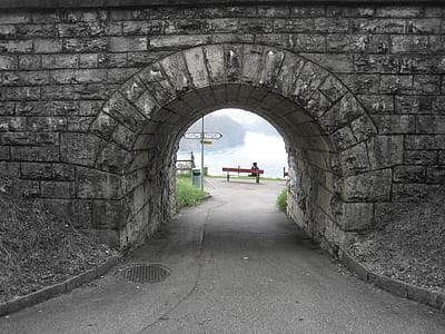 empty gray concrete underground tunnel near red benches and body of water at daytime thumbnail