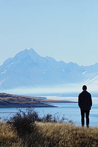 man standing on hill with overview of body of water thumbnail