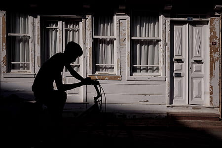 silhouette of person riding bicycle along wooden houses thumbnail
