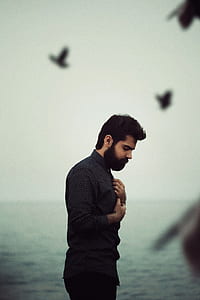 man holding his dress shirt standing near ocean during daytime thumbnail