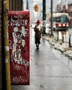 red, white, and black abstract painting near person walking on concrete pathway thumbnail