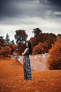 woman in black and gray floral sleeveless dress near brown trees during daytime thumbnail
