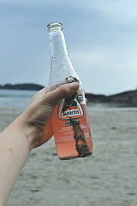 person holding clear glass bottle thumbnail