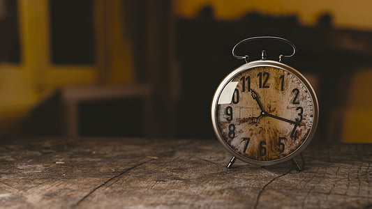 white alarm clock on top of gray wooden table thumbnail
