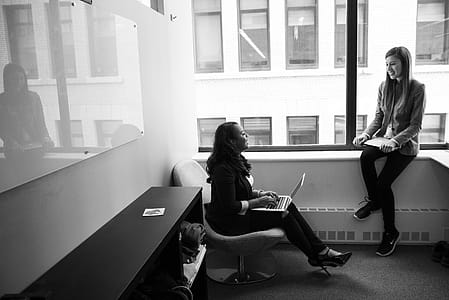 Grayscale Photo of Woman Talking to Her Colleague thumbnail