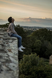 man sitting on the edge of stone pavement during sunset thumbnail