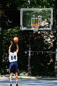 man shooting basketball towards ring outdoor during daytime thumbnail