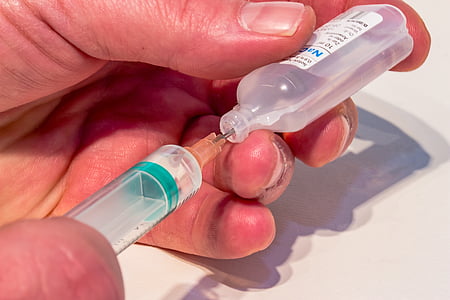 person holding syringe and plastic bottle thumbnail