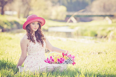 photo of a woman sitting on ground holding bouquet of basket flower thumbnail