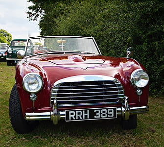 vintage red vehicle parked near trees thumbnail