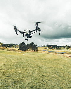 white and black quadcopter drone in mid air under white clouds thumbnail