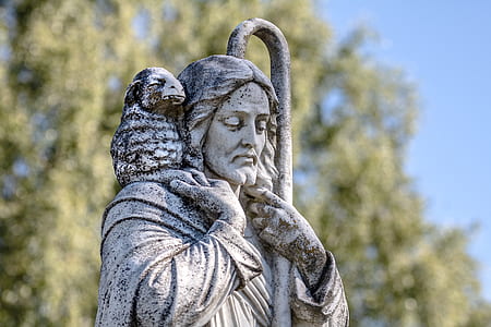 man standing holding rod and lamb religious statue at daytime thumbnail