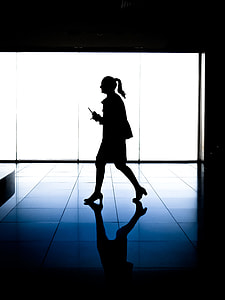 silhouette of woman holding stick walk near glass wall thumbnail