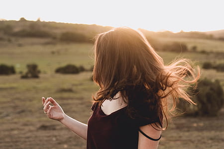 woman in maroon v-neck t-shirt looking at green pasture thumbnail