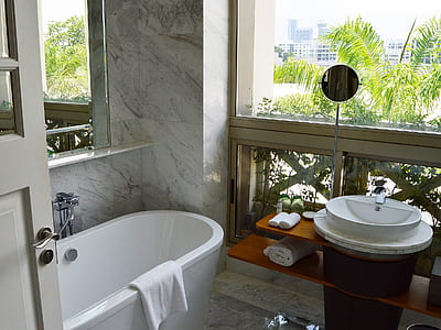 bath tub near glass window and vanity sink thumbnail