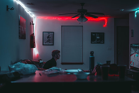 photograph of man seating on sofa playing NBA thumbnail