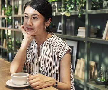 Woman Seated Near a Shelf Holding Coffee Cup thumbnail