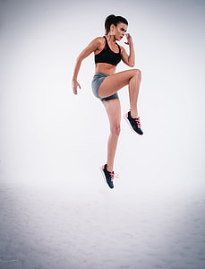 woman wearing black sports bra and gray short shorts and pair of black shoes doing exercise thumbnail