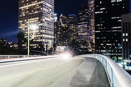 photography of empty road near high rise buildings at nighttime thumbnail
