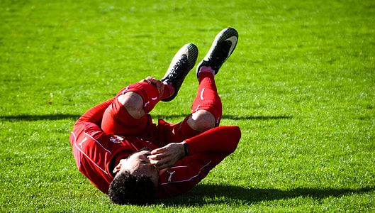 injured soccer player holding his left leg while lying on field thumbnail