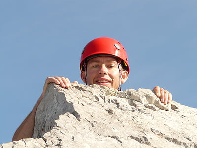 man with red hard hat on top of grey rock formation thumbnail