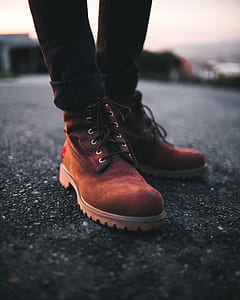 Person Wearing Pair of Brown Timberland Work Boots and Black Denim Skinny Jeans Standing on Asphalt Road thumbnail
