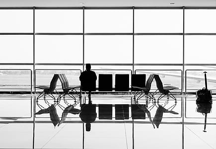 silhouette of a man sitting in front of airport windowpane thumbnail