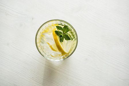 top-view photography of drinking glass with sliced lemon and green leaf water thumbnail