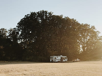 white type A motorhome parked near sedan and trees thumbnail