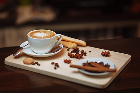coffee with heart cream and cinnamon stick on white ceramic saucer thumbnail