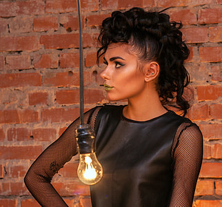 woman standing near brown brick wall with turned-on filament bulb thumbnail