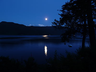 body of water and mountains during night time thumbnail
