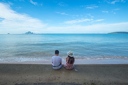 Man and Woman Sitting on Seashore thumbnail