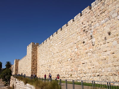 people walking beside of brown wall during daytime thumbnail