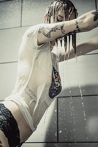 woman taking shower while two hands on tiles thumbnail