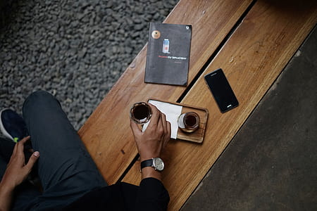 photo of person sitting on bench and holding glass thumbnail