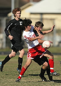 three men playing soccer during daytime thumbnail