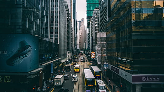 vehicles on roadway between high rise buildings during daytime thumbnail