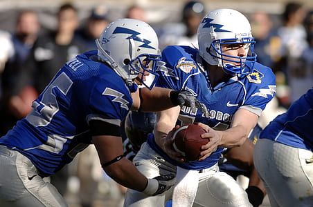 two football players holding brown football thumbnail