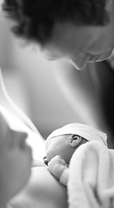 grayscale photo of man facing baby on woman's chest thumbnail
