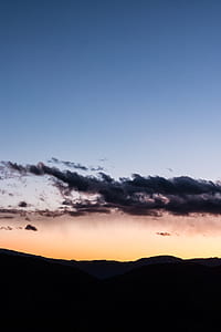 silhouette of mountains under cloudy sky during sunset thumbnail