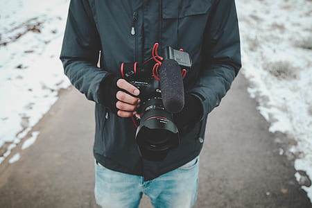 person wearing blue dress shirt holding black DSLR camera thumbnail
