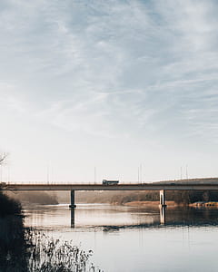 calm body of water near bridge under cloudy sky thumbnail