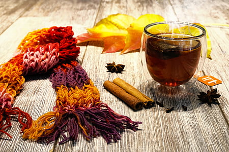 knitted scarf beside dried leaf and shot glass on wooden surface thumbnail