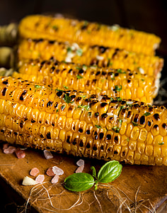 four grilled corn on top of brown wooden table thumbnail
