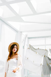 woman wearing white camisole and brown hat standing near white curtain thumbnail