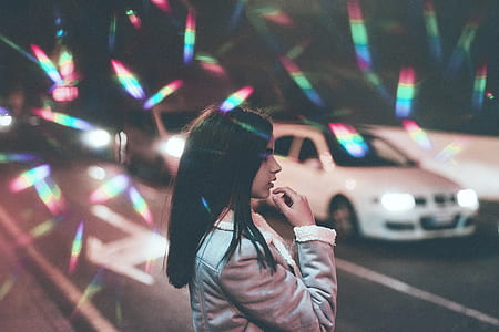 girl standing on street near white car at nighttime thumbnail
